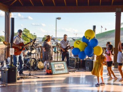 Girl with a handful of balloons watching the live band.