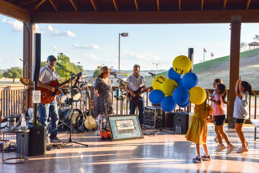 Girl with a handful of balloons watching the live band.